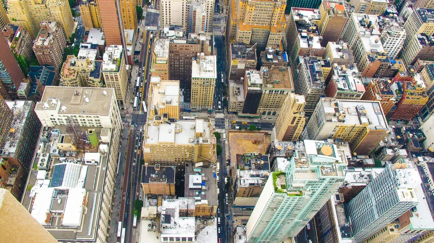Aerial view of dense city rooftops and flat commercial roofs.