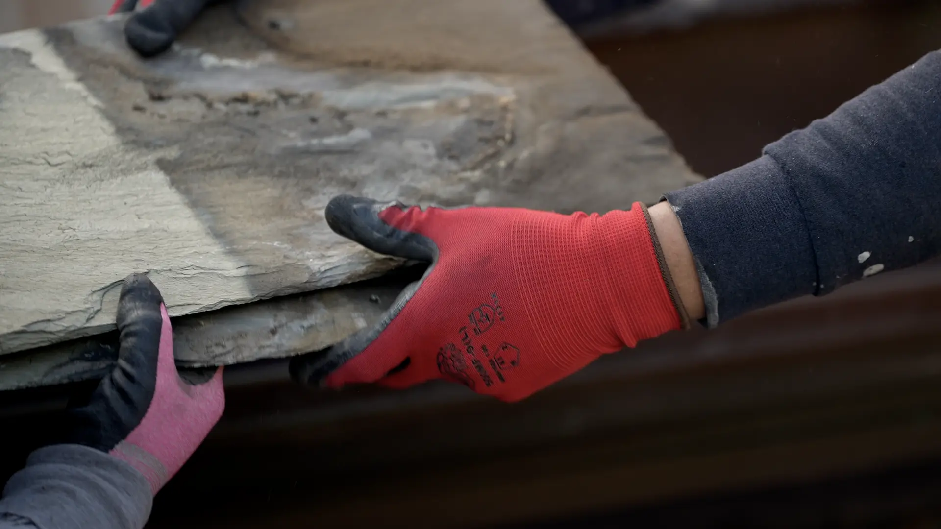 Two Crown crew members handling slate tiles on a job site.