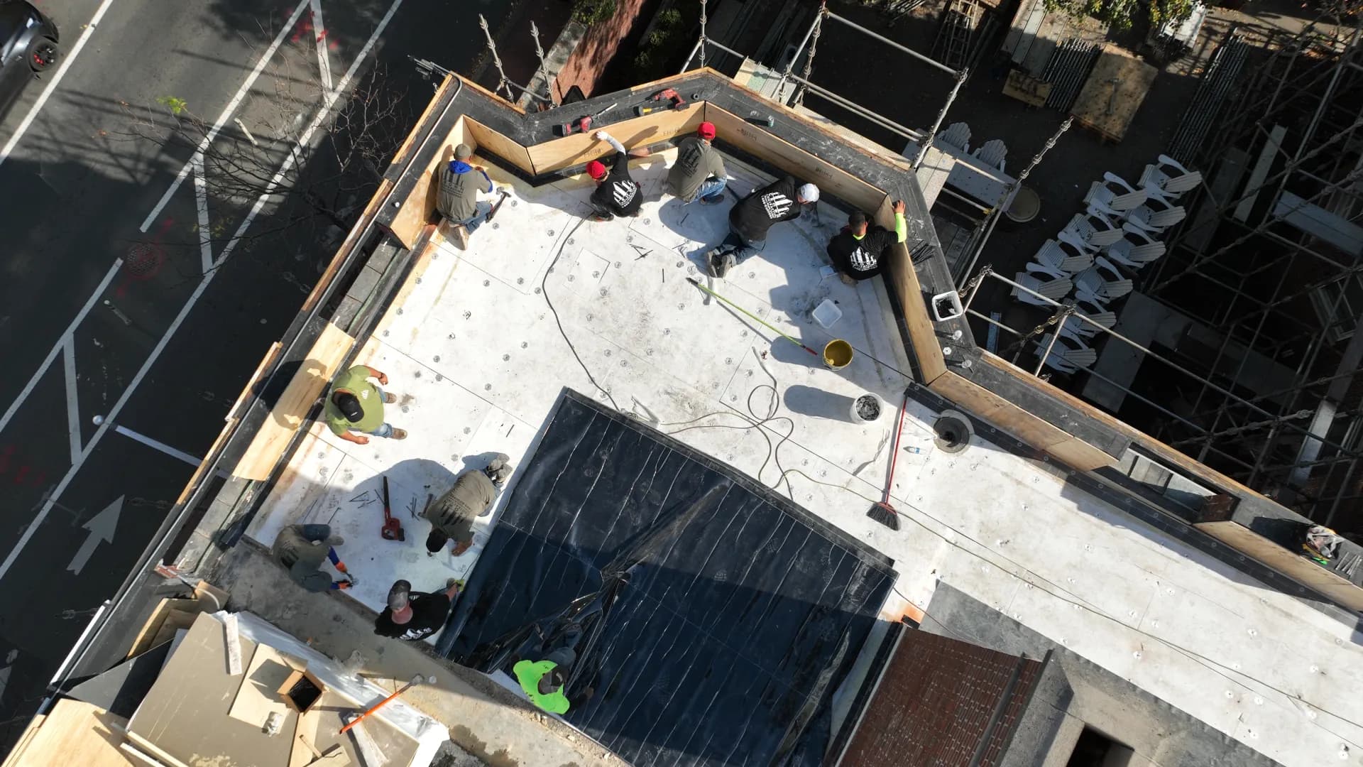 Aerial view of a Crown Contracting crew installing a new flat roof system on a city building.