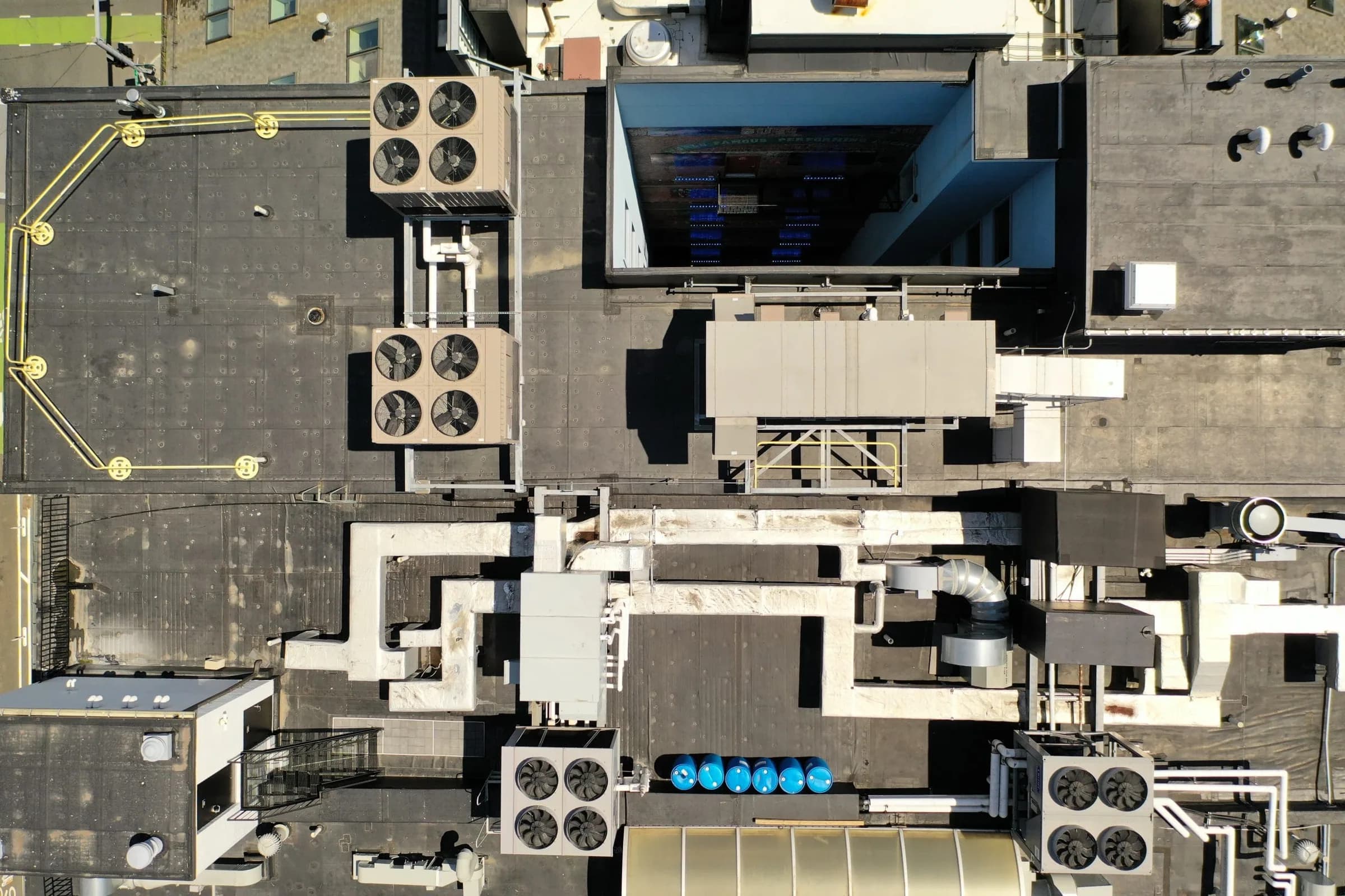 Overhead view of a commercial flat roof with rooftop HVAC units, equipment curbs, and a safety rail.