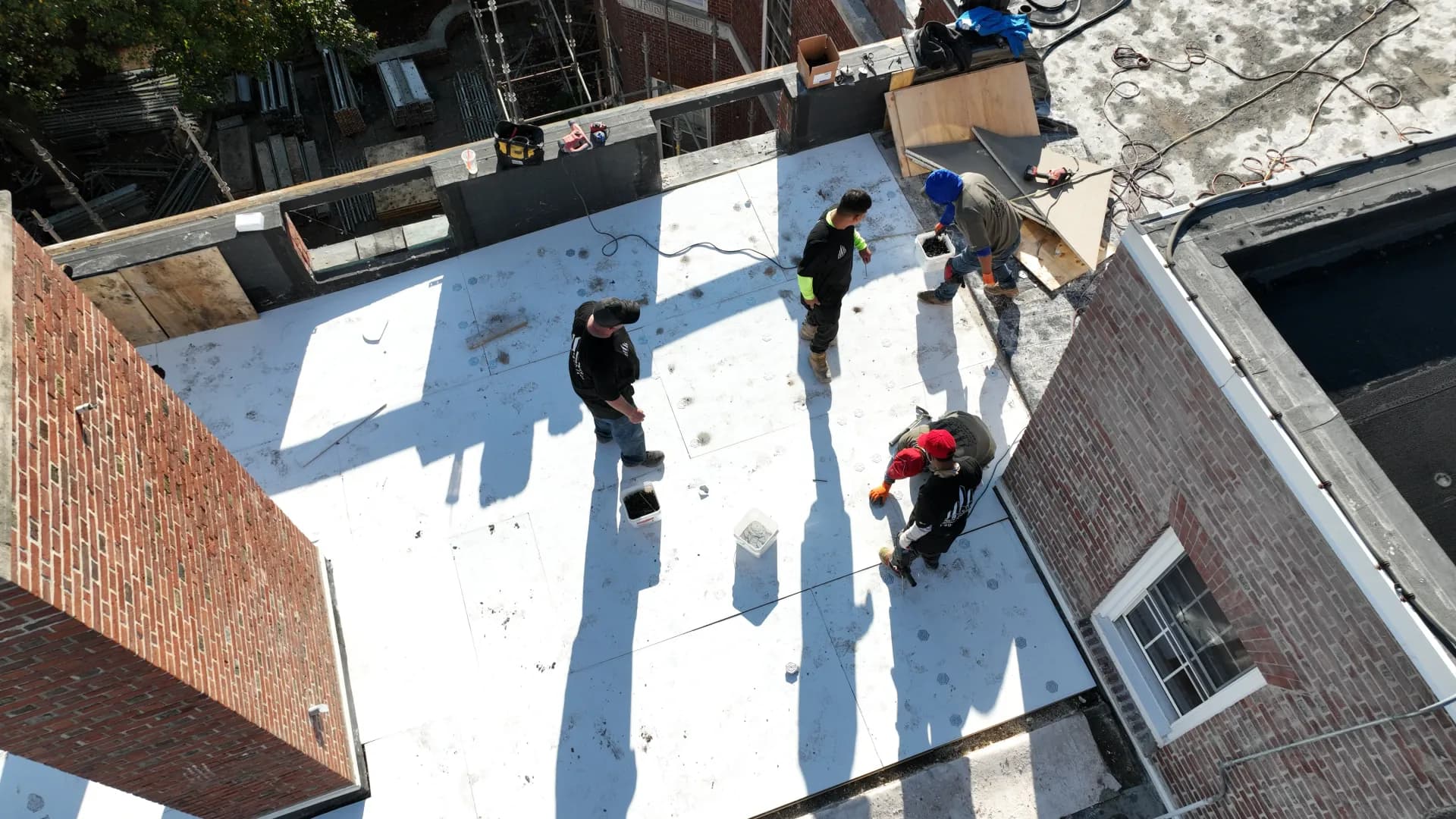 Crown Contracting crew working on a white single-ply membrane roof between Boston brick walls.