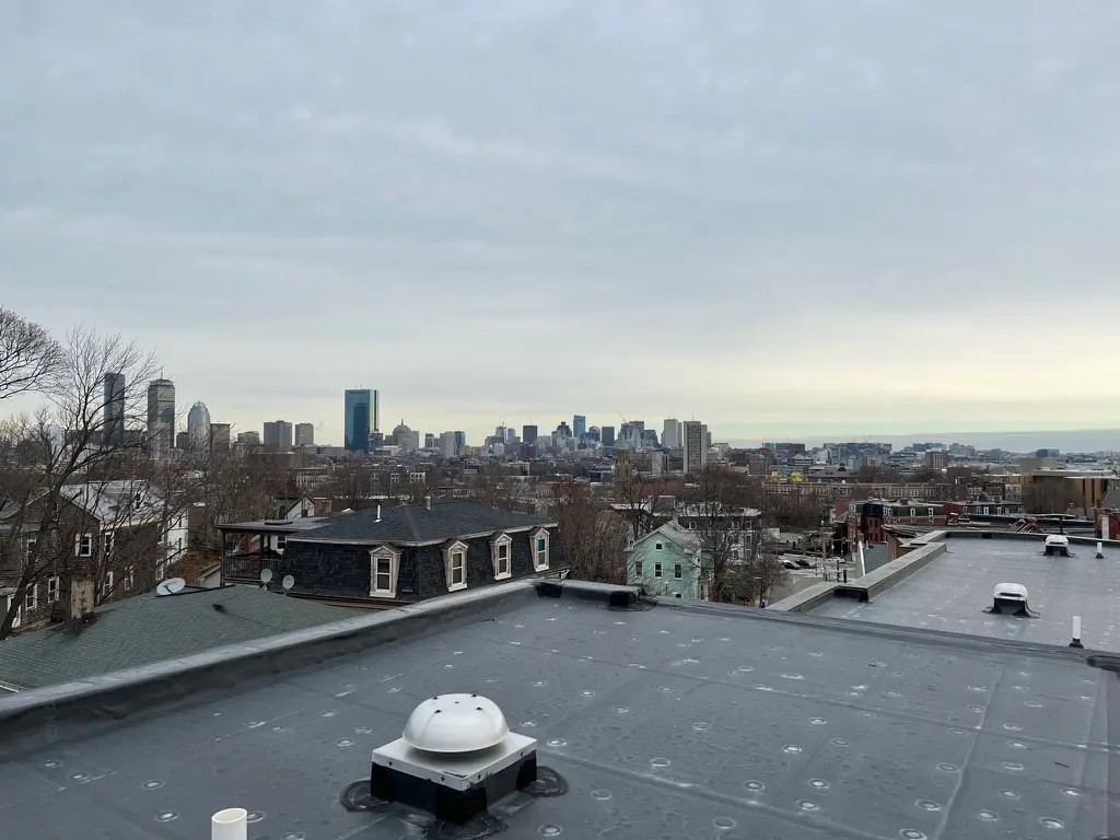 Finished commercial flat roof looking out over a Boston neighborhood and the downtown skyline.