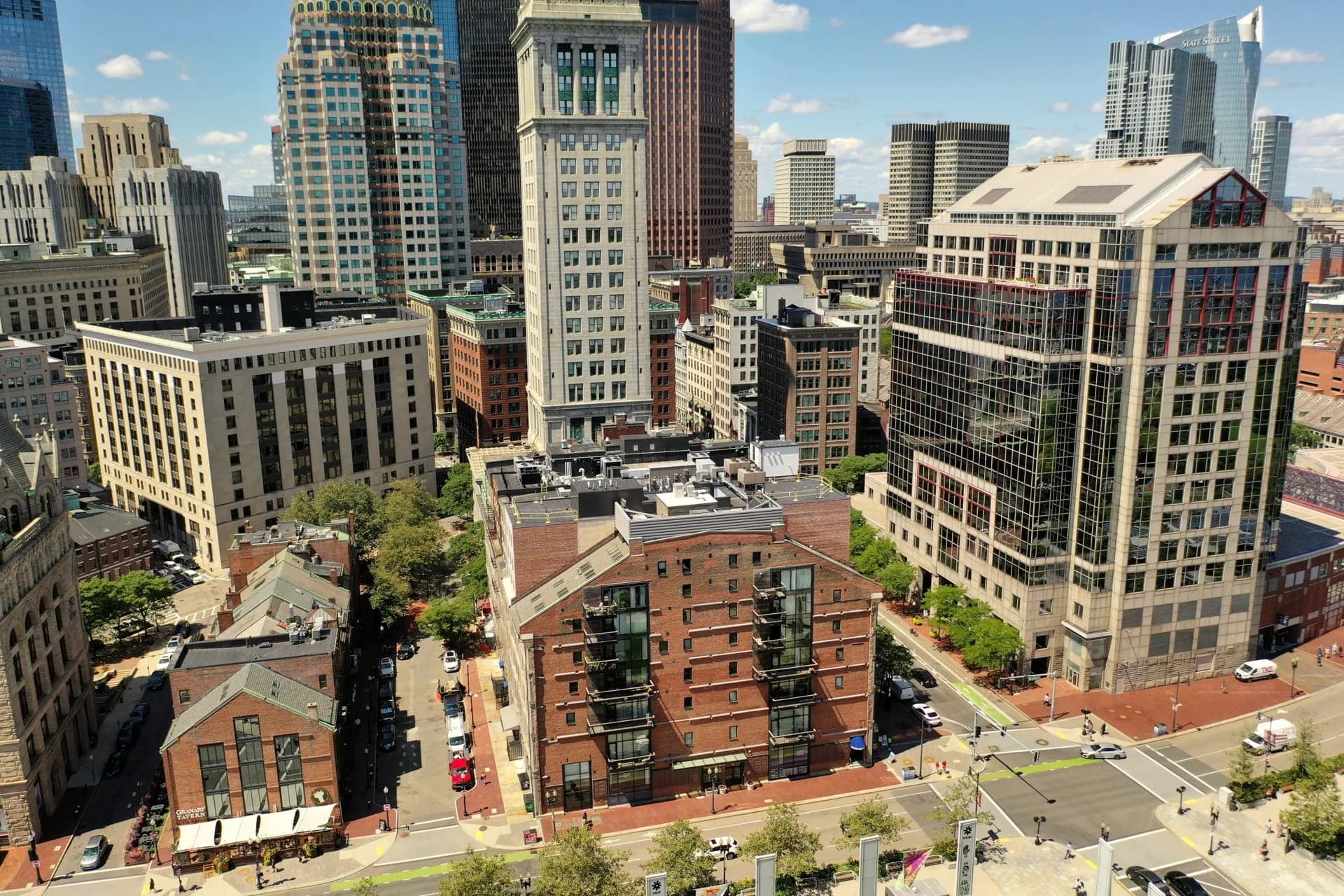Aerial view of the Harborside Inn's brick hotel block in downtown Boston, with the Custom House Tower and the financial district behind it.