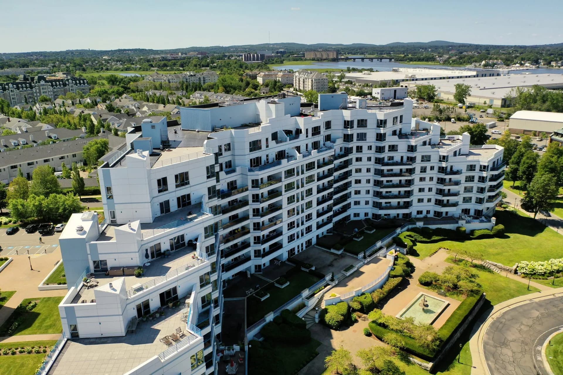 Aerial view of the Marina Point Condominiums in Quincy, a stepped white residential high-rise above a landscaped courtyard on Marina Bay.