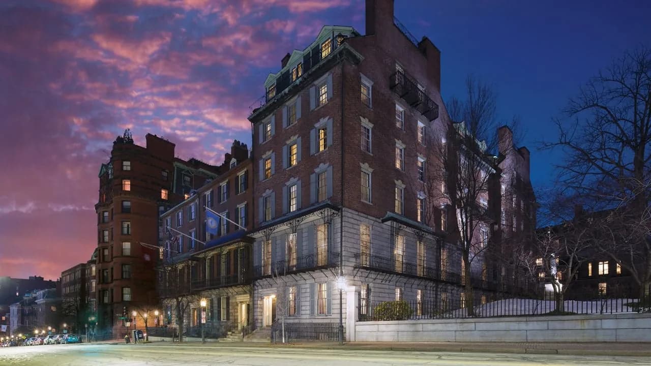 Northeastern University President's Building on Beacon Street at dusk, brick and granite with iron balconies and a copper-trimmed mansard roof.