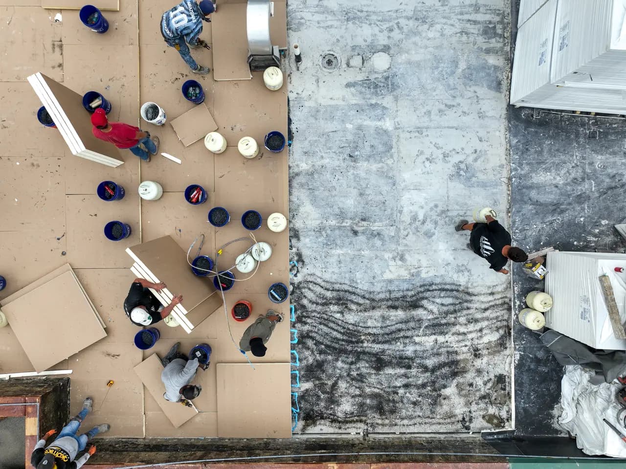 Top-down view of a Crown crew laying insulation boards on a commercial roof replacement.