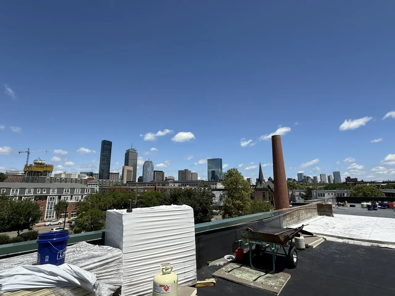 Materials staged on a commercial flat roof with the Boston skyline behind.