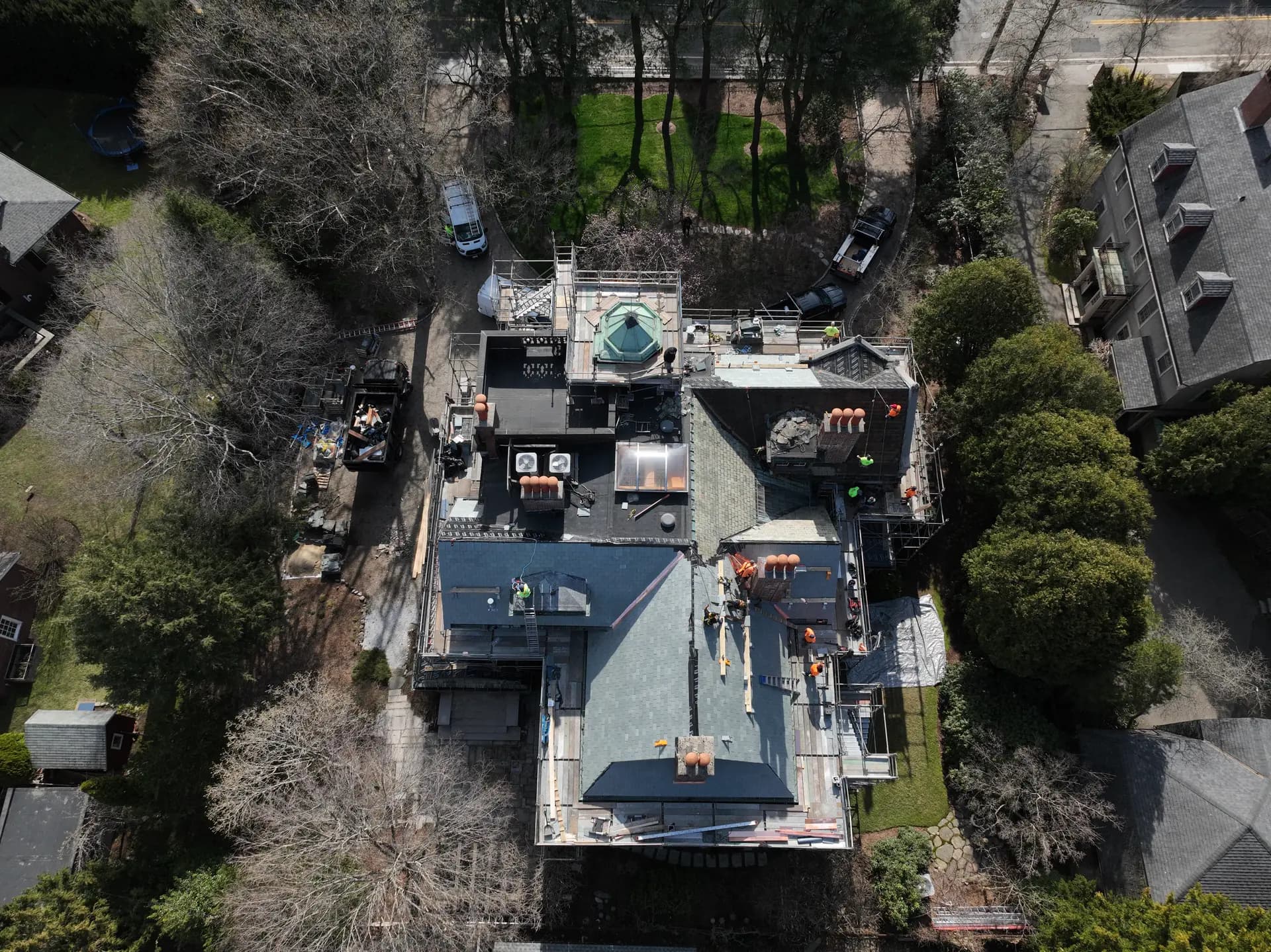 Aerial view of a Crown crew restoring a complex slate and copper roof.