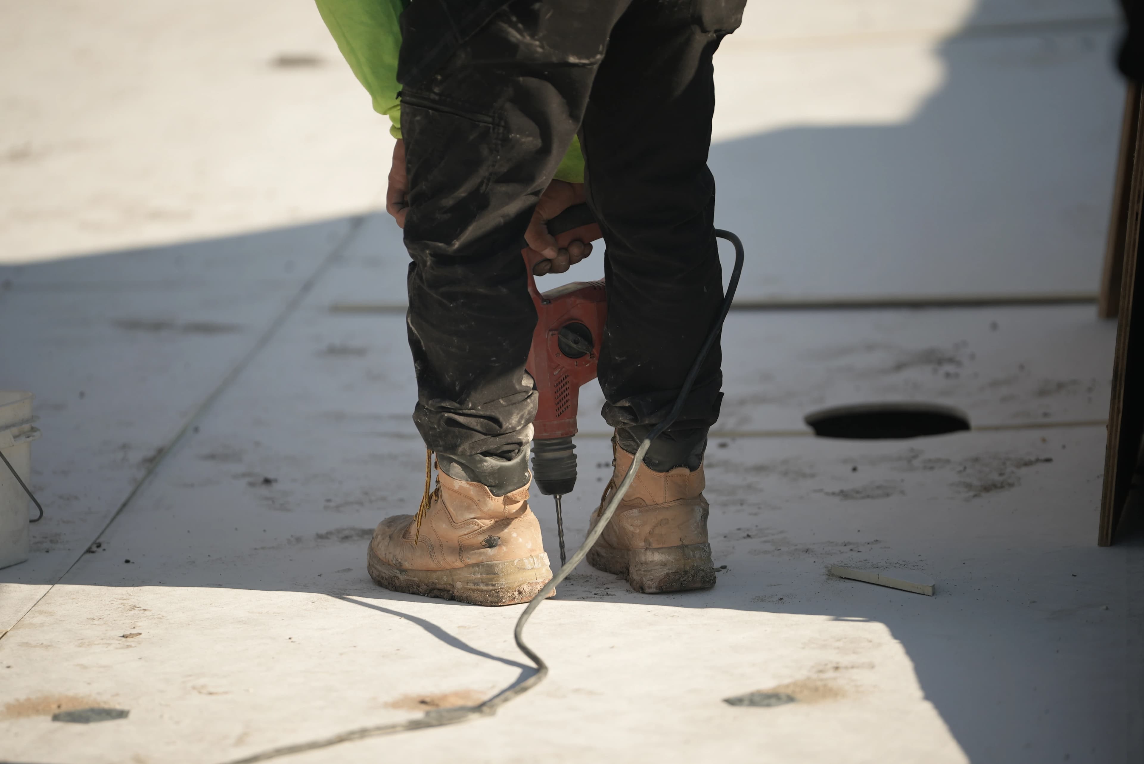 Roofer mechanically fastening insulation plates through new flat roof membrane.
