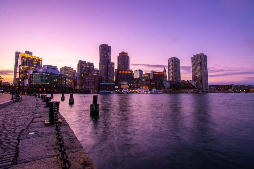 Boston Harbor waterfront and the downtown skyline at dusk.