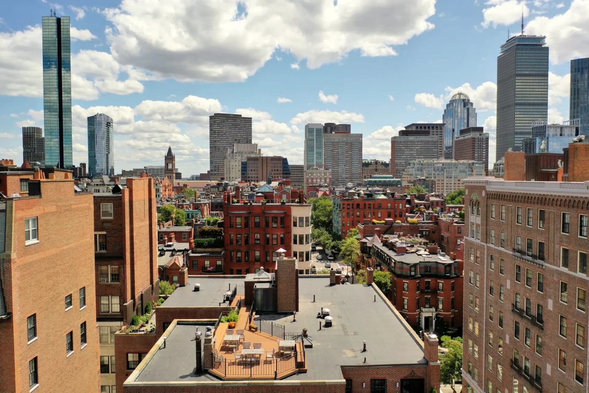 Flat and low-slope Boston rooftops in the foreground with the downtown skyline behind.